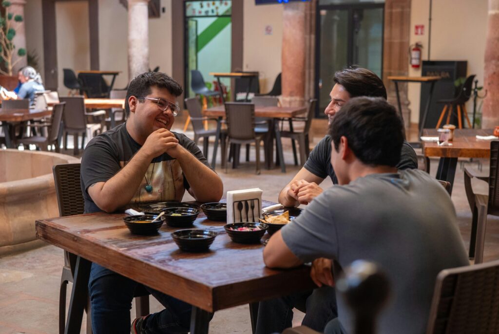 Three friends sharing a meal and conversation in an authentic Mexican restaurant setting.